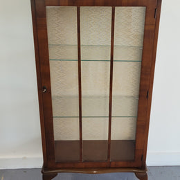 Petite single door Walnut display cabinet. Art Deco style with glass display door and two fixed shelves. In original condition.