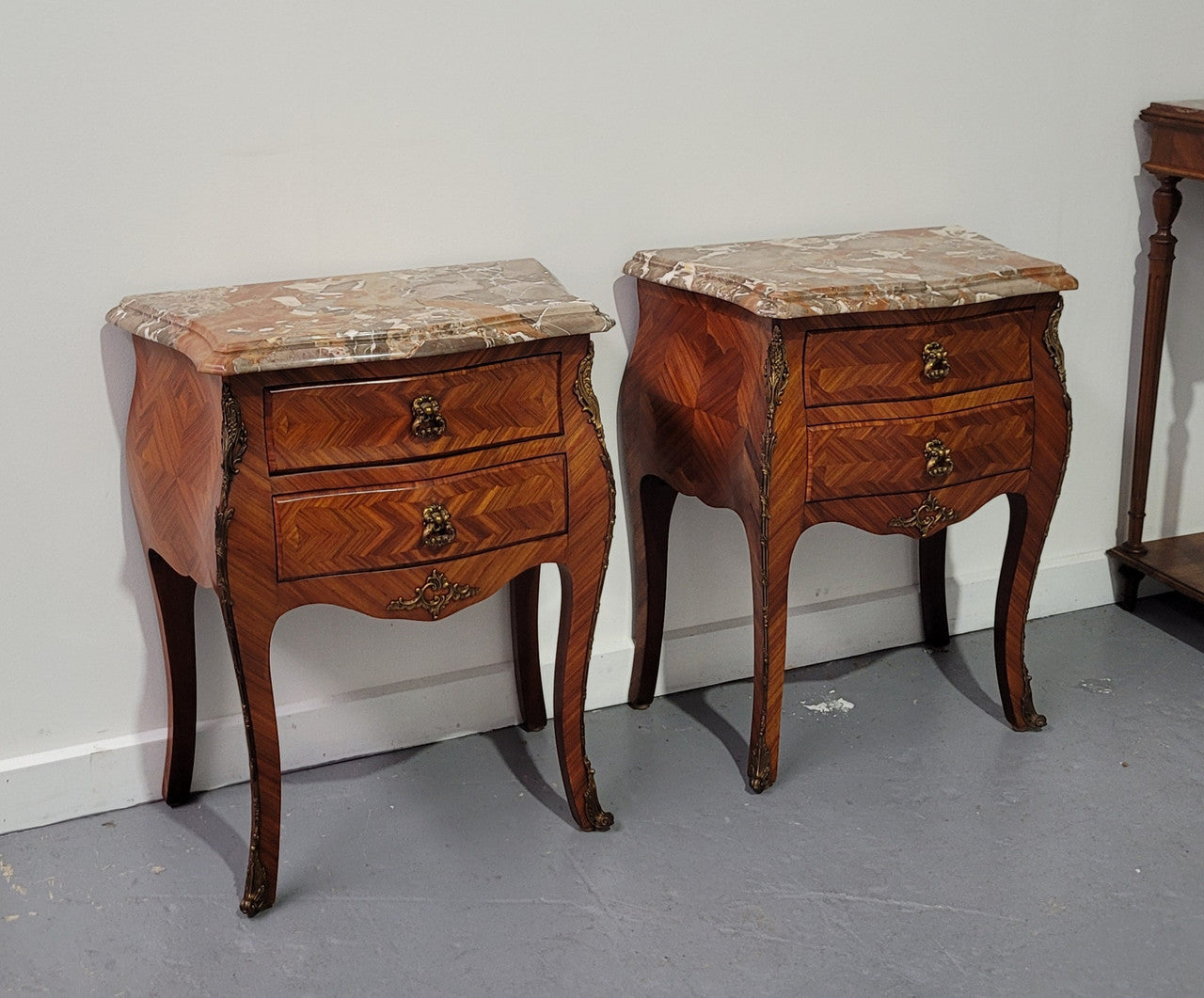 Pair of Louis XV commode style two drawer bedsides with beautiful marble tops and decorative mounts. They are a rare size and are in good, detailed condition.