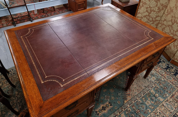 Substantial French Louis XVI style Oak partners desk. It has a beautiful leather top, two drawers on either side and decorative carvings throughout. Sourced from France and in good original detailed condition.