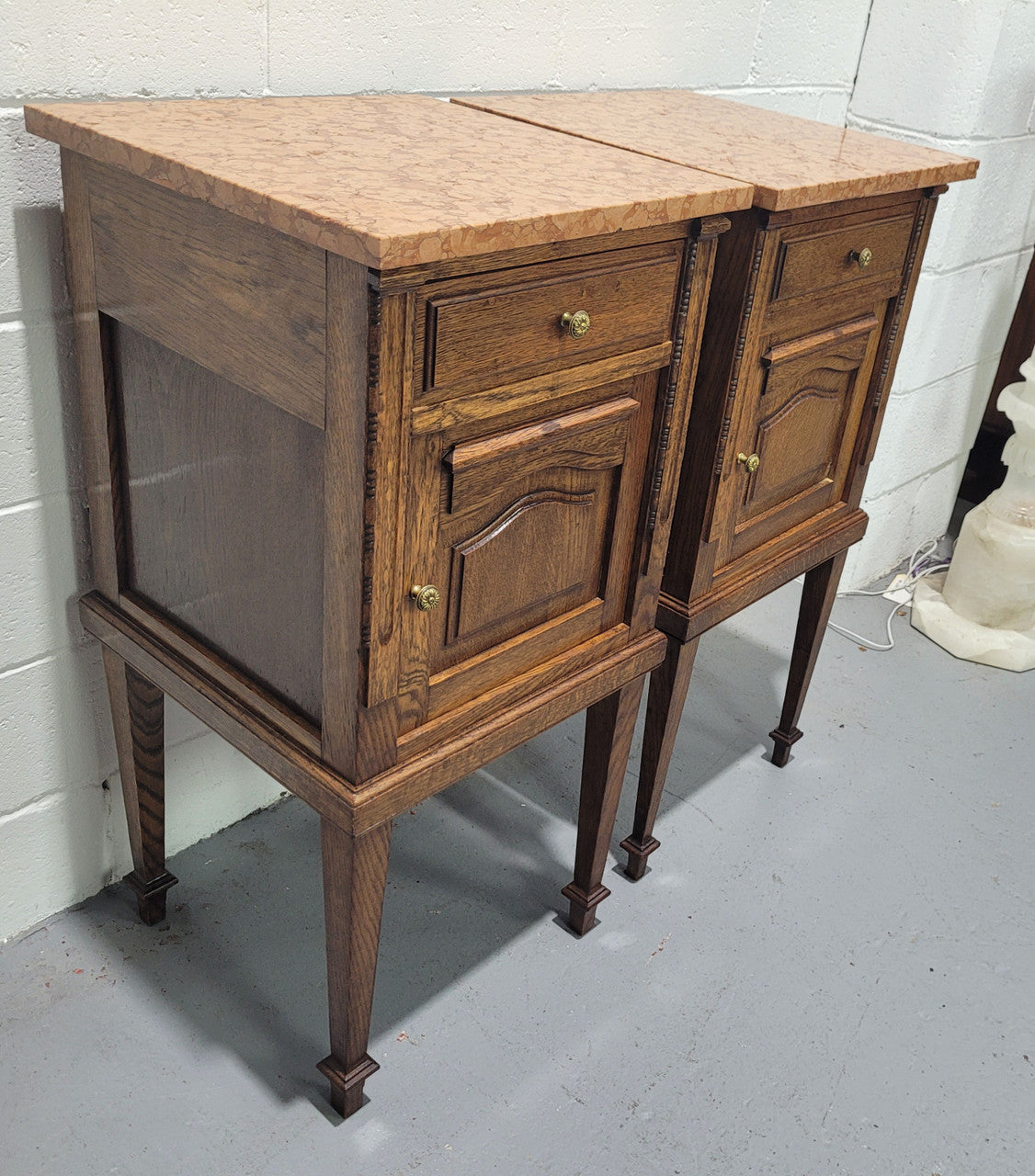 Beautiful pair of French oak bedside cabinets with marble tops. They have a drawer and cupboard for storage and are in good original detailed condition.