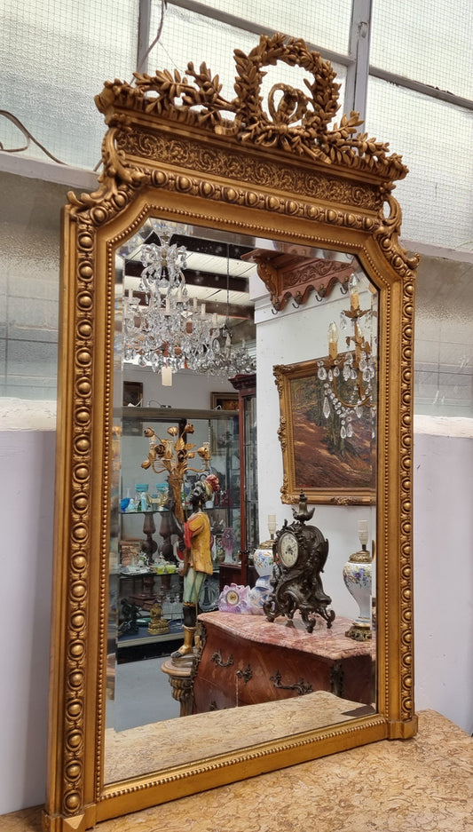 A stunning Napoleon III gilt mantle mirror with its original mirror. The top of the mirror is decorated with a beautiful laurel wreath and detailed decorative carving throughout. It is in good original condition with the bevelled mirror showing natural aging please view photo's.