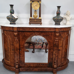 An elegant Antique Victorian Burr wood Walnut marble-top sideboard credenza with a mirrored center door. It has a white shaped marble top, mirror front, nicely carved details and three swing doors along with two keys. It is in good original detailed condition.