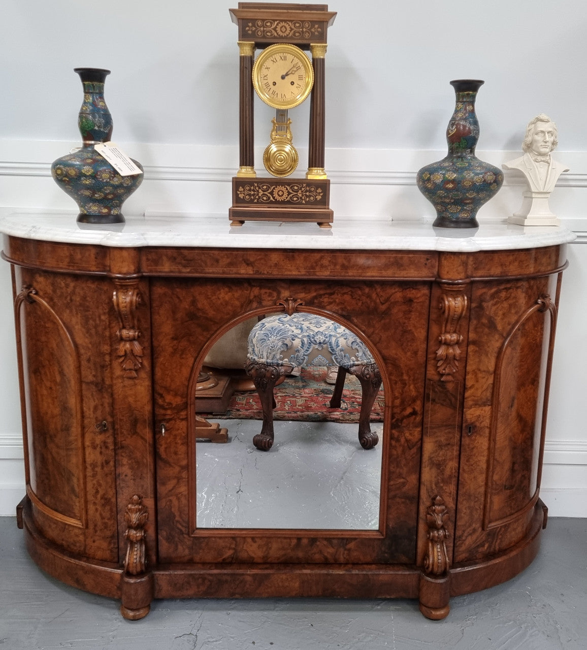 An elegant Antique Victorian Burr wood Walnut marble-top sideboard credenza with a mirrored center door. It has a white shaped marble top, mirror front, nicely carved details and three swing doors along with two keys. It is in good original detailed condition.
