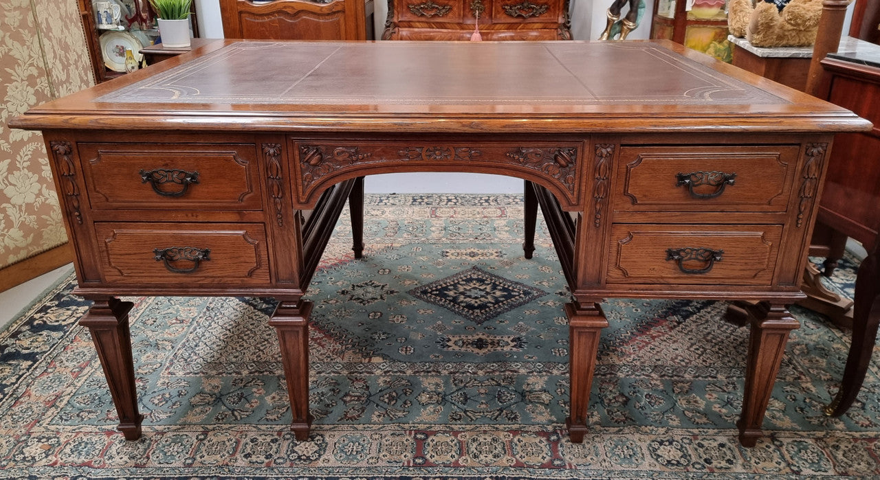 Substantial French Louis XVI style Oak partners desk. It has a beautiful leather top, two drawers on either side and decorative carvings throughout. Sourced from France and in good original detailed condition.