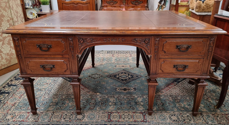 Substantial French Louis XVI style Oak partners desk. It has a beautiful leather top, two drawers on either side and decorative carvings throughout. Sourced from France and in good original detailed condition.