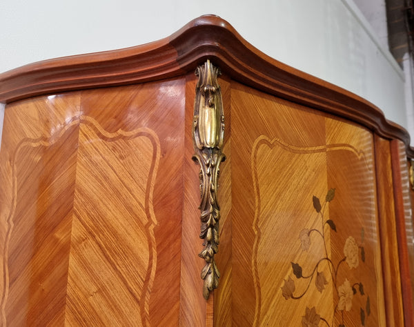 Tall French Marquetry inlaid armoire / bookcase with ormolu mounts. The interior has six fully adjustable shelves and two drawers. It is in good original detailed condition.