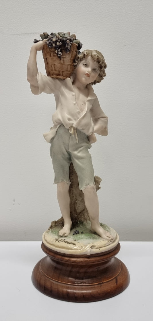 Lovely Italian figurine of boy carrying basket with grapes on a wooden base. It is signed Giuseppe Armani and 1982 FLORENCE. In good original condition.  Please view photos as they form part of the description.