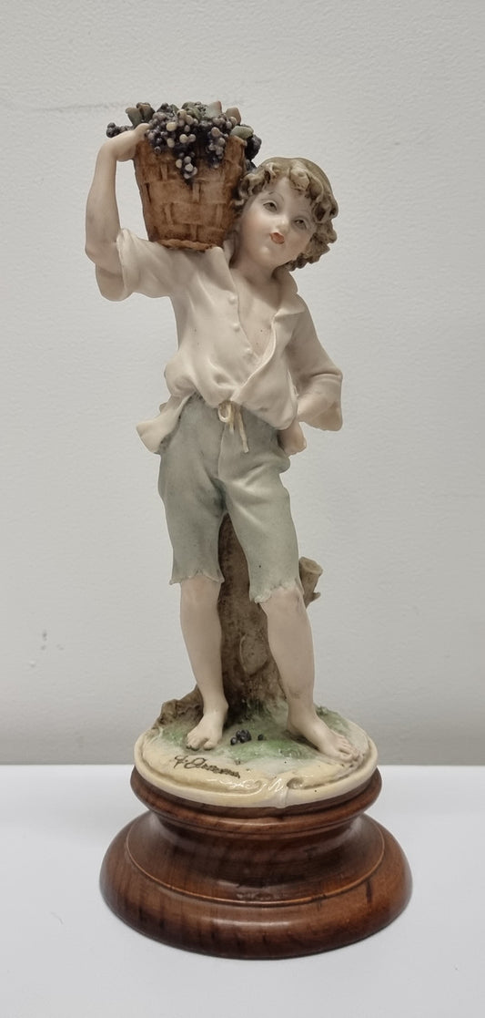 Lovely Italian figurine of boy carrying basket with grapes on a wooden base. It is signed Giuseppe Armani and 1982 FLORENCE. In good original condition.  Please view photos as they form part of the description.
