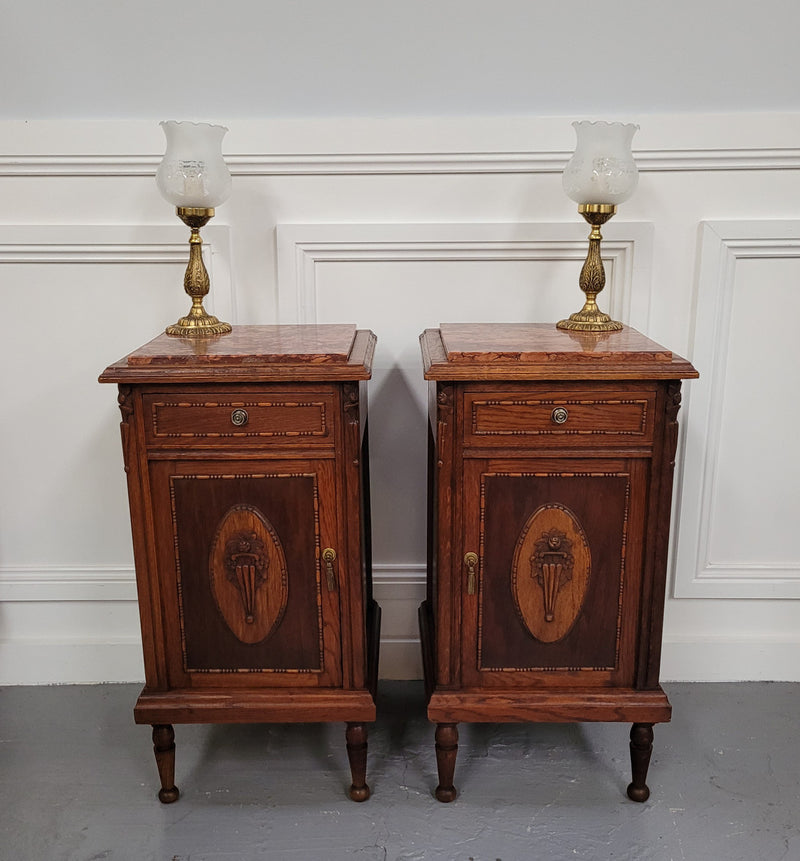 Pair of French Art Deco Oak and rouge inset marble top bedside cabinets. They have one drawer and one cupboard with elegant carving on the door. They have been sourced from France and are in good original detailed condition.