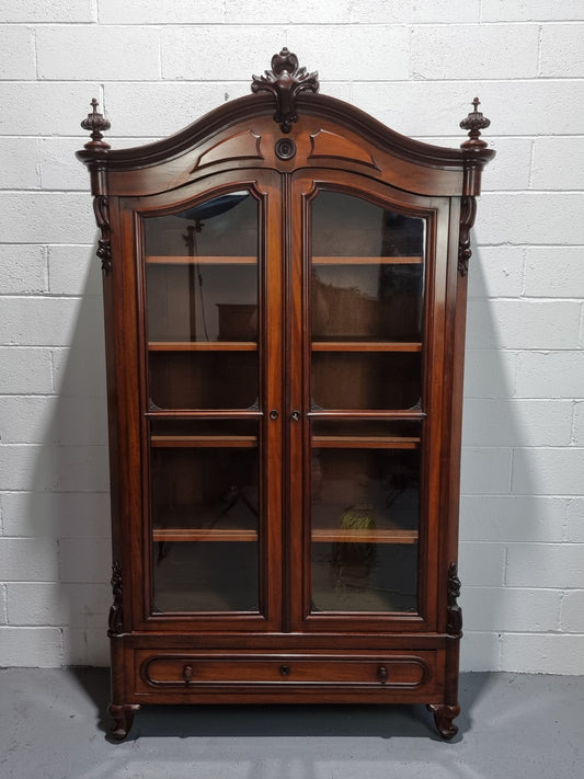 Antique Mahogany two door Biedermeier style bookcase with four fully adjustable shelves and a drawer at the bottom. The two wooden finials at the top are easily removed for a different look of desired. In good original detailed condition.