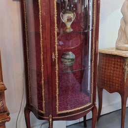 French Mahogany two shelf vitrine with curved glass and brass mounts. It has a lovely frabic interior and two glass shelves. In good original detailed condition.