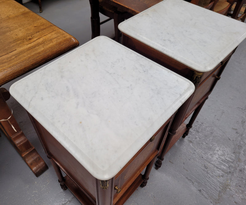 Pair of white marble topped Louis 16th style bedside cabinets consisting of one drawer and one cupboard.  Inlaid with burr walnut and has decorative mounts. They have been sourced from France and are in good original condition.
