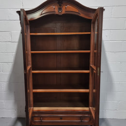 Antique Mahogany two door Biedermeier style bookcase with four fully adjustable shelves and a drawer at the bottom. The two wooden finials at the top are easily removed for a different look of desired. In good original detailed condition.