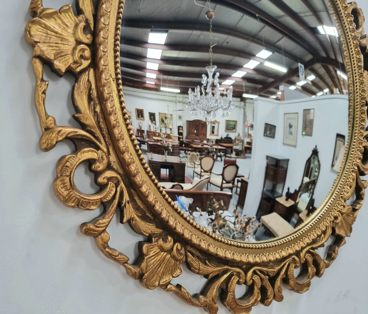 Large round convex mirror in a decorative carved wood gilt frame. In good original detailed condition.