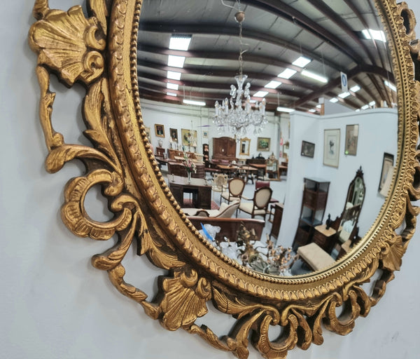 Large round convex mirror in a decorative carved wood gilt frame. In good original detailed condition.