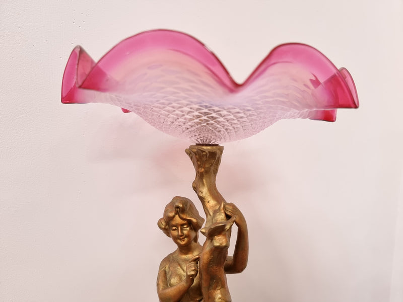 Late Victorian spelter table Centerpiece/comport featuring a woman holding an opalescent and ruby glass bowl. In good original condition with no damage to the ruby bowl.