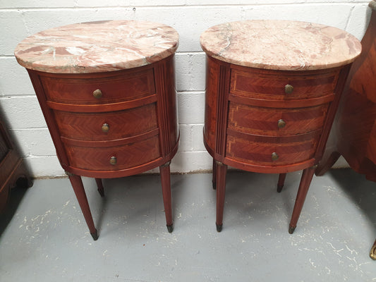 Rare pair of oval Louis XVI style inlaid bedside drawers, with beautiful marble tops. They are in very good restored condition. Circa 1920's.