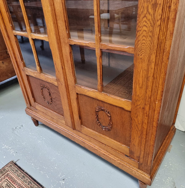 French light Oak two door bookcase with four adjustable shelves. It has beautiful decorative carving and is in good original detailed condition.