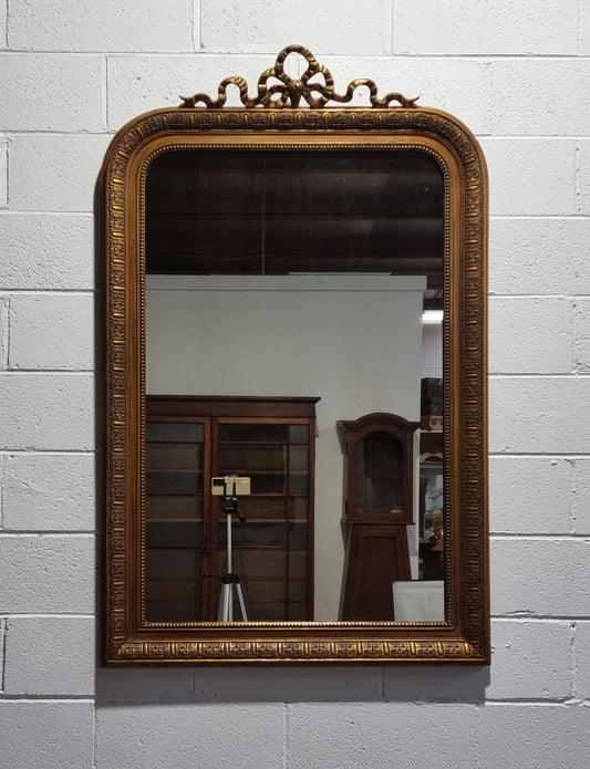 Late 19th century French gilt mirror with beautiful ribbon crest on top. In good original detailed condition.