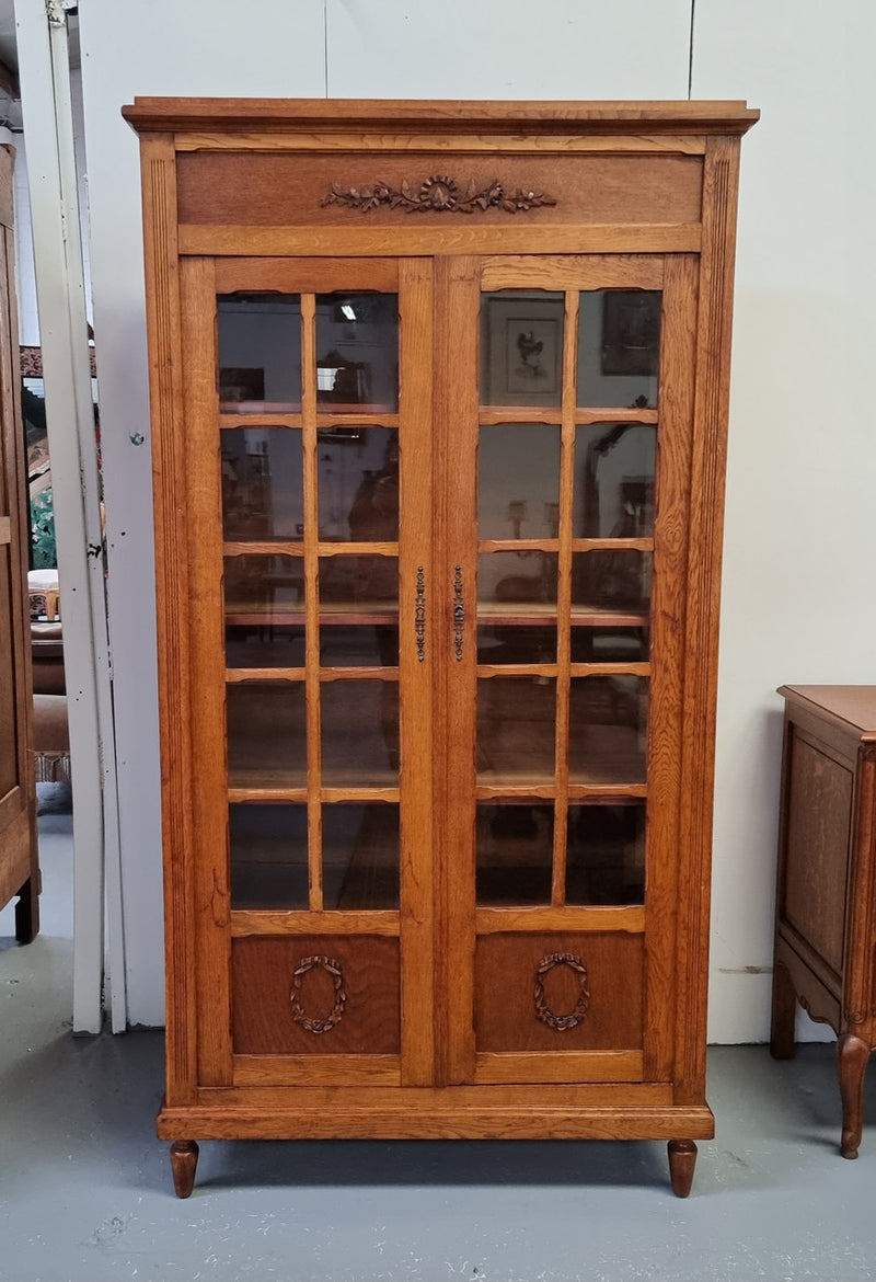 French light Oak two door bookcase with four adjustable shelves. It has beautiful decorative carving and is in good original detailed condition.