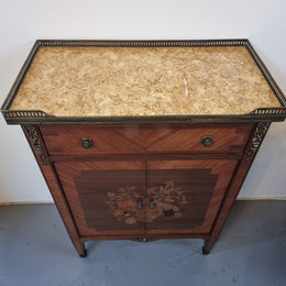 Louis 16th style marquetry inlaid side cabinet with a pierced brass gallery surrounding a marble top. It has two doors open up to storage with one shelf and a drawer above that. In good original detailed condition.