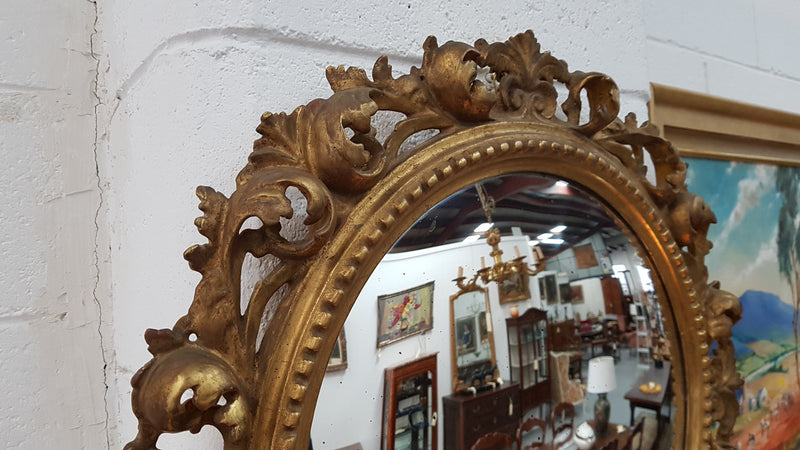 Large round carved wooden convex mirror. Still contains its original mirror which shows signs of aging.