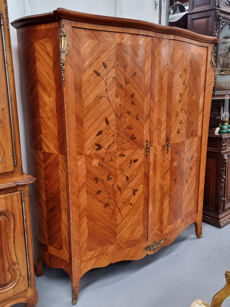 Charming French Louis XV Style Marquetry Inlaid Two Door Armoire. Features three adjustable shelves and ormolu trim. It has been sourced from France and is in good original condition.