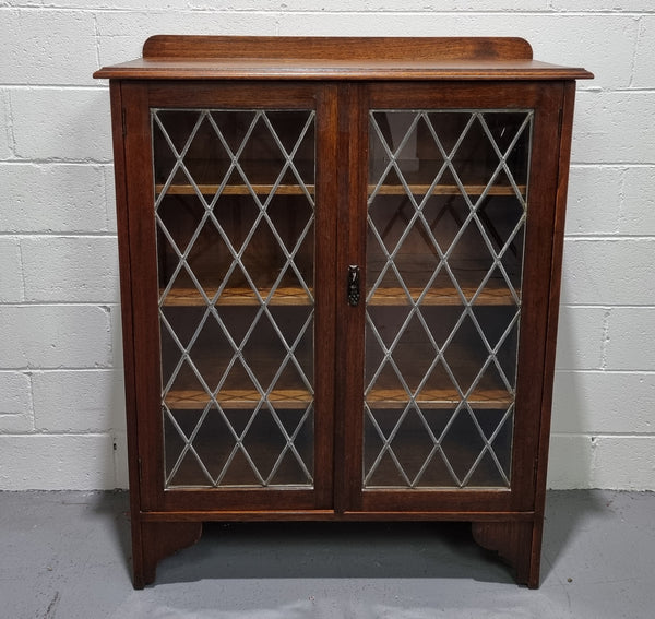 Lovely leadlight two door Oak bookcase/display cabinet with four wooden shelves. It is in good original detailed condition.