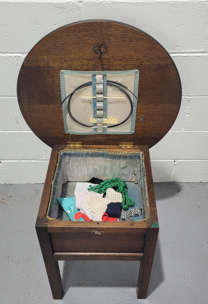 Fabulous round oak side table which also has a hidden sewing box underneath with lovely original blue satin lining and Includes pictured sewing items. It is in good original condition.