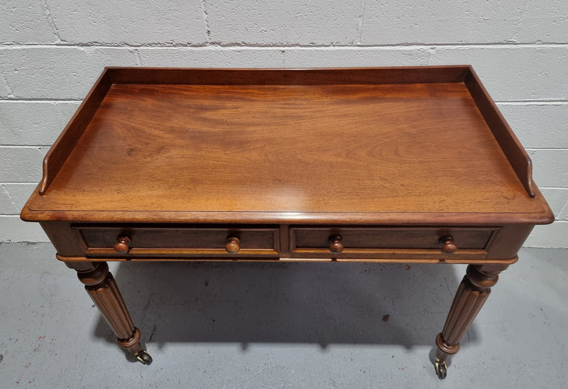English Victorian Mahogany side table or desk with two drawers and gallery, fluted legs and ceramic castors. In good original condition.