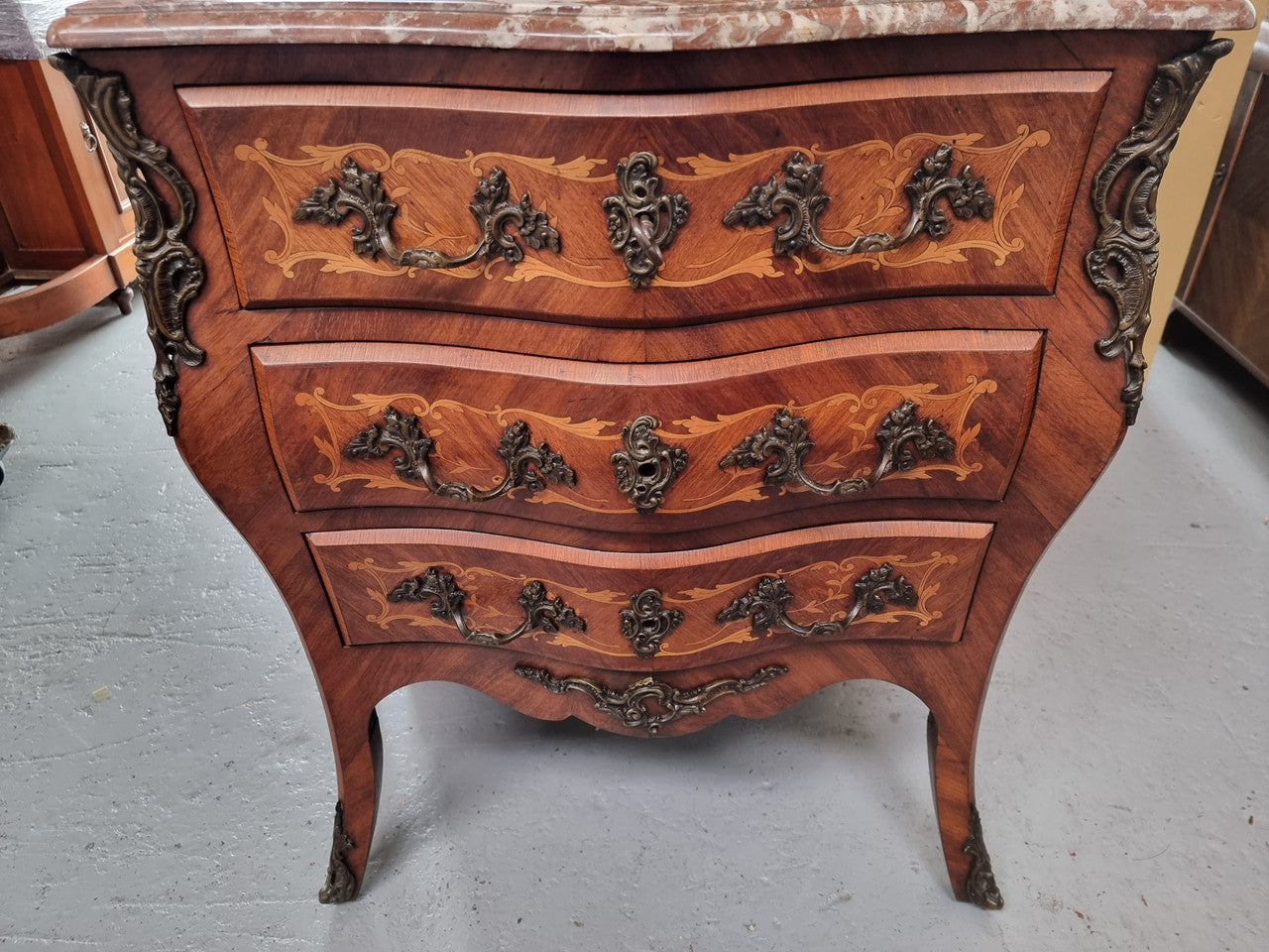 Antique French Louis XV style compact three drawer marble top commode with marquetry inlay and ormolu mounts. Sourced from France and in good original detailed condition.