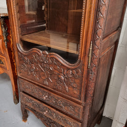 Petite oak armoire display cabinet with a glass door, two drawers at the bottom and three shelves inside. Late 18th Century and amazing detailed decorative carvings. Sourced from France and in good original condition.